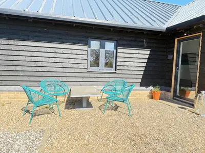 three blue chairs and a table in front of a house at Beautiful 2 Bedroom Barn -Stansted Airport 2 miles in Elsenham