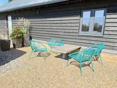 three blue chairs and a table in front of a house at Beautiful 2 Bedroom Barn -Stansted Airport 2 miles in Elsenham