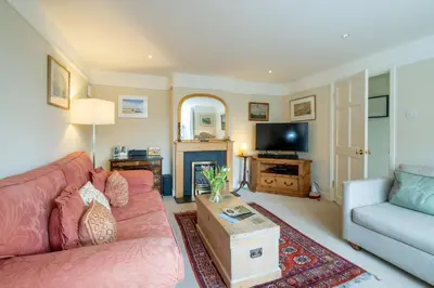 a living room with a pink couch and a tv at 8 Lee Road, Aldeburgh - Aldeburgh Coastal Cottages in Aldeburgh