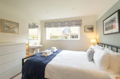 a bedroom with a bed and a sink and a window at 8 Lee Road, Aldeburgh - Aldeburgh Coastal Cottages in Aldeburgh