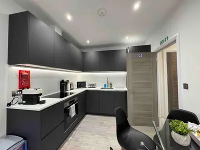 a kitchen with black cabinets and a black chair at Castle Hill Apartments Colchester in Colchester