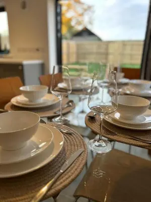 a table with plates and wine glasses on it at Mango Cottage in Thorndon