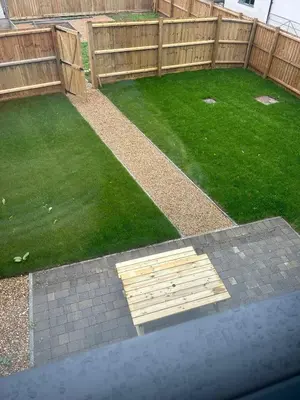 a garden with a wooden fence and green grass at Mango Cottage in Thorndon