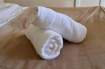 a rolled up white towel on a bed at Deben Cottage, Central Woodbridge in Woodbridge