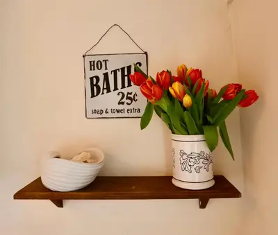 a vase of tulips on a wooden shelf with a sign at Deben Cottage, Central Woodbridge in Woodbridge