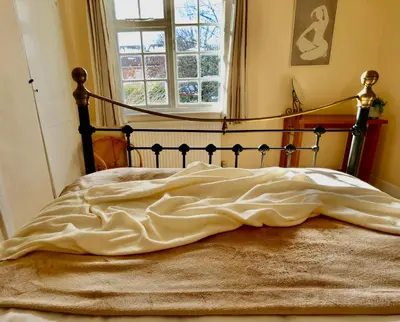 an unmade bed in a bedroom with a window at Deben Cottage, Central Woodbridge in Woodbridge