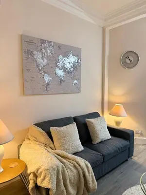 a living room with a blue couch and a map of the world at Luxe city stay in Ipswich
