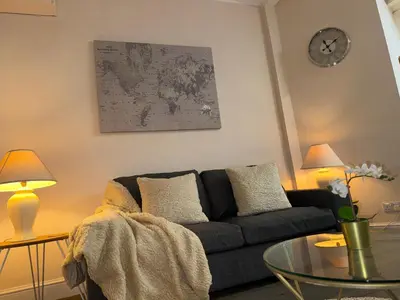 a living room with a couch and a clock on the wall at Luxe city stay in Ipswich