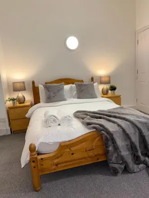 a bedroom with a wooden bed with two towels on it at Luxe city stay in Ipswich
