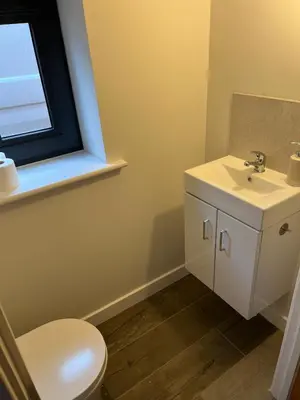 a bathroom with a sink and a toilet and a window at Pineapple Cottage in Thorndon