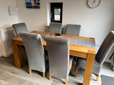 a dining room table with gray chairs around it at Pineapple Cottage in Thorndon