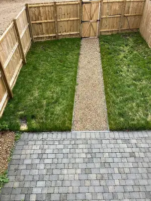 a backyard with a wooden fence and green grass at Pineapple Cottage in Thorndon