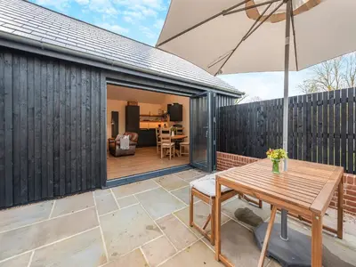 a patio with a wooden table and an umbrella at Maple Barn in Eye