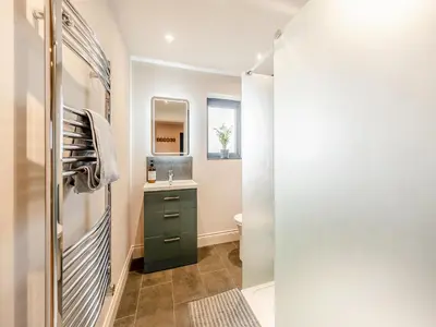 a bathroom with a green cabinet and a mirror at Maple Barn in Eye