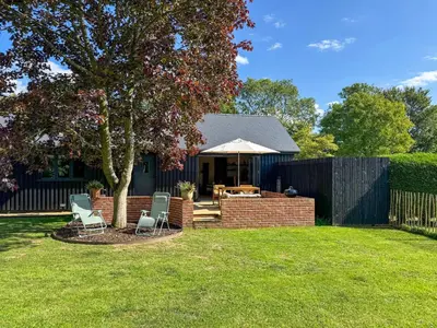 a backyard with chairs and a table and an umbrella at Maple Barn in Eye