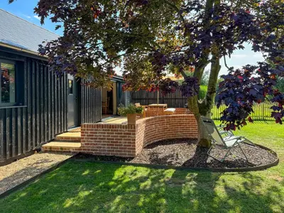 a brick retaining wall around a tree in a yard at Maple Barn in Eye