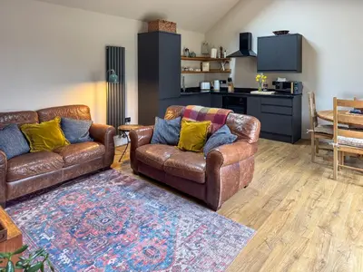 a living room with two leather couches and a kitchen at Maple Barn in Eye