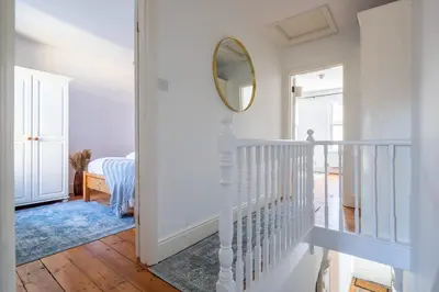 a hallway with a white staircase and a mirror at Stylish 3-Bed Home in the Heart of the Cambridge in Cambridge
