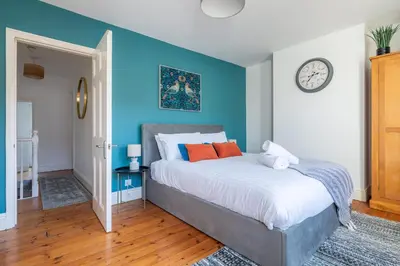 a bedroom with blue walls and a bed with orange pillows at Stylish 3-Bed Home in the Heart of the Cambridge in Cambridge