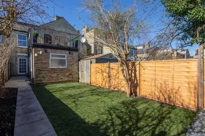 a backyard with a wooden fence and a yard at Stylish 3-Bed Home in the Heart of the Cambridge in Cambridge