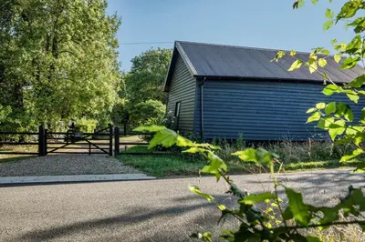 a blue building with a fence next to a road at The Stable Barn, Smallwood Farm House in Hessett