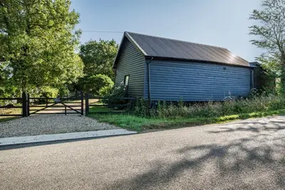 a blue barn sitting next to a road at The Stable Barn, Smallwood Farm House in Hessett