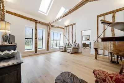 a living room with a piano and a room with windows at The Stable Barn, Smallwood Farm House in Hessett