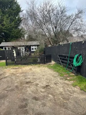 a fence with a green hose hanging from a fence at Be Our Guest in Earls Colne