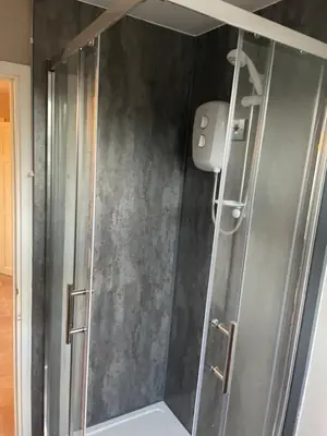 a shower with a glass door in a bathroom at Be Our Guest in Earls Colne