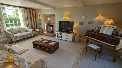 a living room with a piano and a couch at Grade 1 Listed Farm House 14 ppl 45 mins London in Fyfield