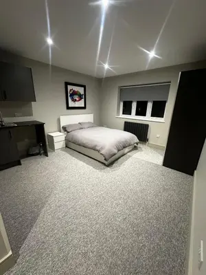 a bedroom with a bed and a desk and two windows at Captivating 7 -Bed House in Waltham Abbey in Waltham Abbey