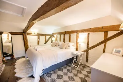 a bedroom with a large bed in a room with wooden ceilings at Wayside Cottage, Dennington in Brundish
