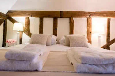 a bedroom with a large bed with two ottomans at Wayside Cottage, Dennington in Brundish