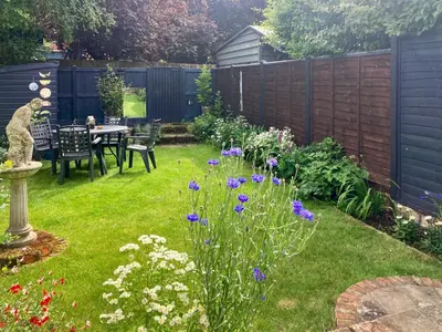 a garden with a table and some flowers at Sunny Meadow Cottage in Sudbury