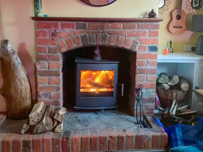 a brick fireplace with a fire in it at Sunny Meadow Cottage in Sudbury