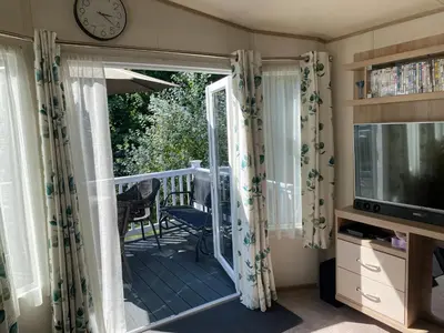 a room with a balcony with a clock and a television at 2 Bed Static Caravan sleeps 6 Saxmunham in Saxmundham