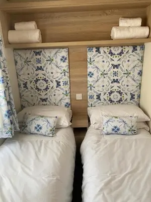 two beds in a room with blue and white wallpaper at 2 Bed Static Caravan sleeps 6 Saxmunham in Saxmundham