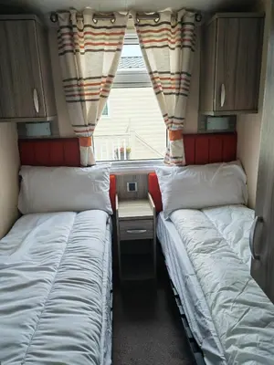 two beds in a small room with a window at Green House Moselle in Jaywick Sands