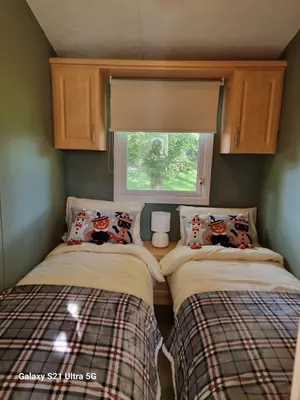 two beds in a small room with a window at The Fox - Free Fishing, pets welcome - static caravan in Clare, Suffolk in Clare