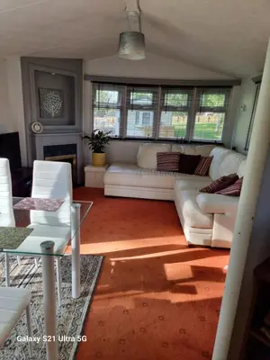 a living room with white couches and a table at The Fox - Free Fishing, pets welcome - static caravan in Clare, Suffolk in Clare