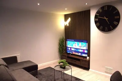 a living room with a clock and a tv at Luxury 3 bedroom house in Harlow, Essex in Harlow