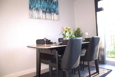 a dining room with a table with chairs and a vase of flowers at Luxury 3 bedroom house in Harlow, Essex in Harlow