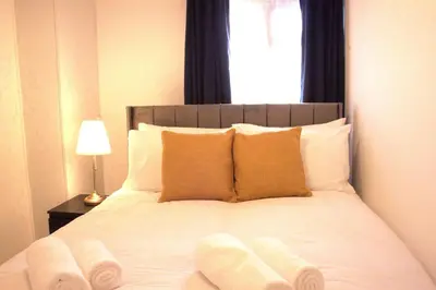 a bed with white socks on it with a window at Luxury 3 bedroom house in Harlow, Essex in Harlow