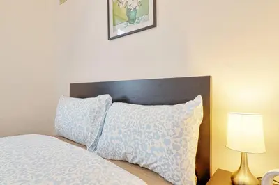 a bed with a headboard and a pillow and a lamp at Spacious 4 Bedroom Home - Sleeps Up to 9 Guests in Chelmsford