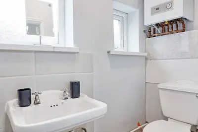 a white bathroom with a sink and a toilet at Spacious 4 Bedroom Home - Sleeps Up to 9 Guests in Chelmsford