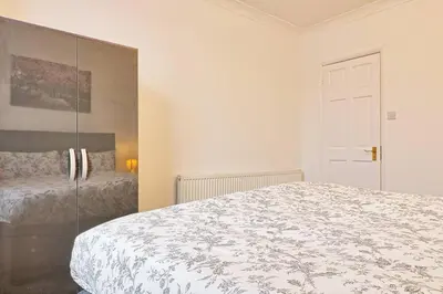 a white bedroom with a bed and a mirror at Spacious 4 Bedroom Home - Sleeps Up to 9 Guests in Chelmsford