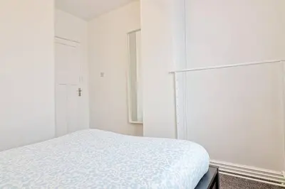 a white bedroom with a bed and a refrigerator at Spacious 4 Bedroom Home - Sleeps Up to 9 Guests in Chelmsford