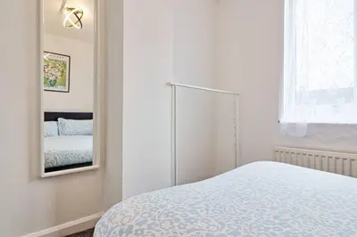 a white bedroom with a bed and a mirror at Spacious 4 Bedroom Home - Sleeps Up to 9 Guests in Chelmsford