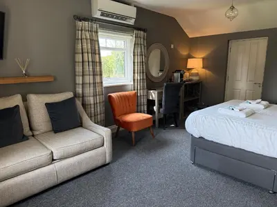a bedroom with a bed and a couch and a chair at Elveden Inn in Elveden