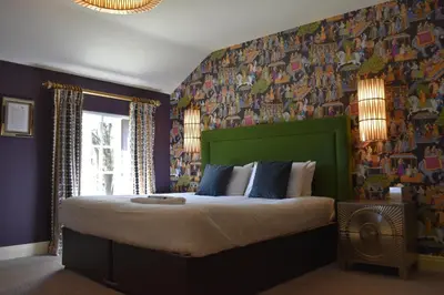 a bedroom with a large bed with a green headboard at Elveden Inn in Elveden